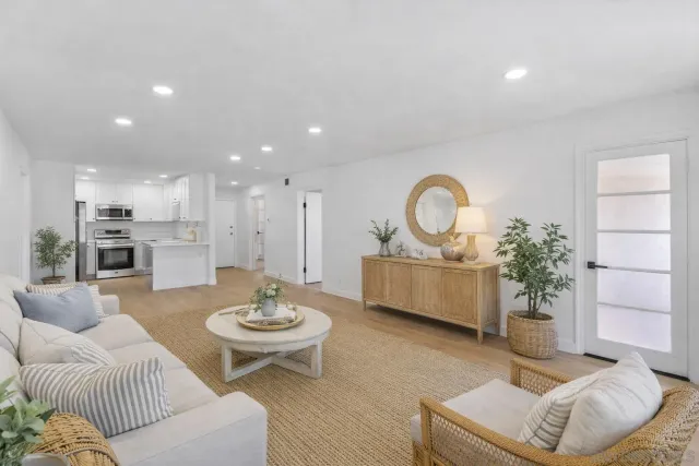 a living room with furniture a mirror and a view of kitchen