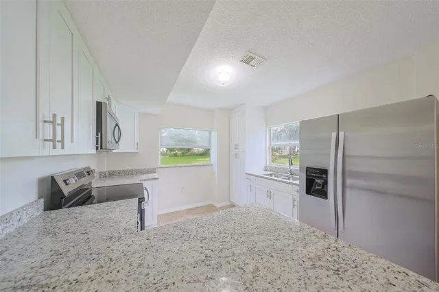 a kitchen with granite countertop a sink stove and refrigerator
