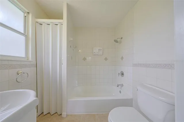 an empty room with windows and chandelier fan