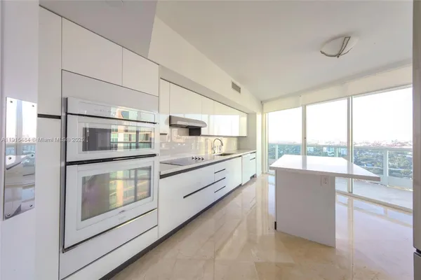 a large kitchen with stainless steel appliances wooden floor and a large window