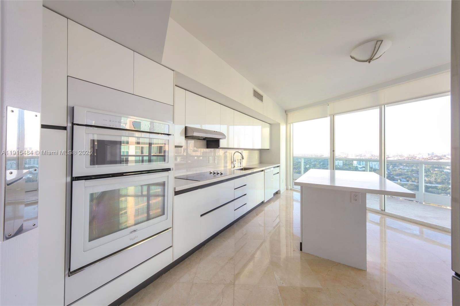 2127 Brickell Avenue, Unit 2504 Miami, FL 33129 - Photo 13 of 41 a large kitchen with stainless steel appliances wooden floor and a large window
