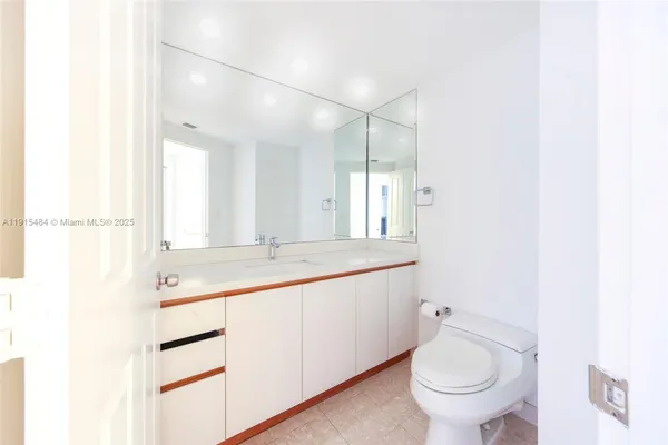 a bathroom with a granite countertop sink mirror vanity and toilet