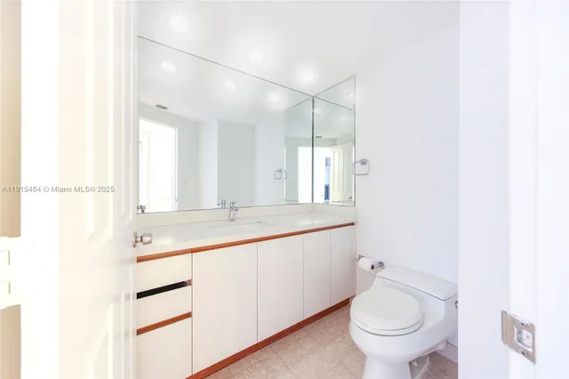 a bathroom with a granite countertop sink mirror vanity and toilet