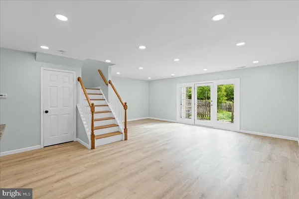 an empty room with wooden floor staircase and windows