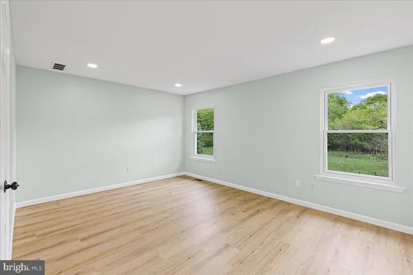 an empty room with wooden floor and windows