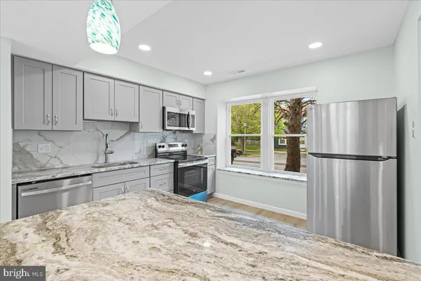 a kitchen with granite countertop a refrigerator and a stove top oven