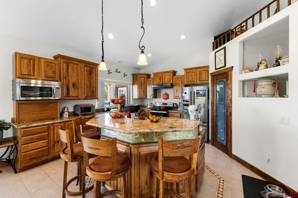 a view of kitchen with stainless steel appliances granite countertop dining table and chairs