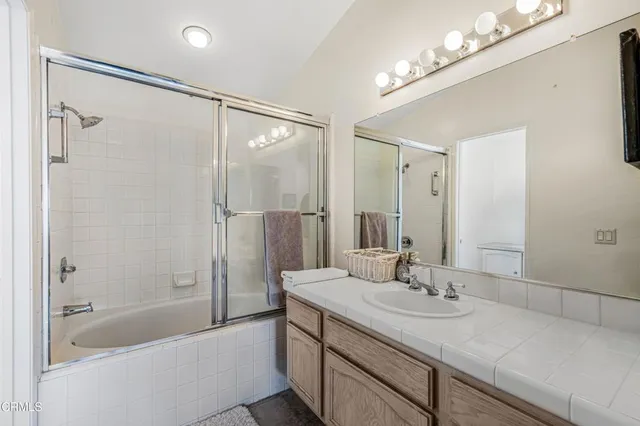 a bathroom with a granite countertop sink a mirror a shower and a bathtub
