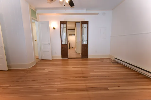 a view of an empty room with wooden floor and a window
