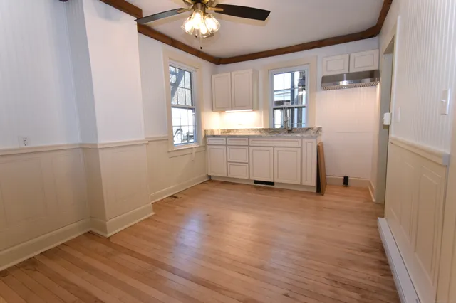 a view of an empty room with window and wooden floor