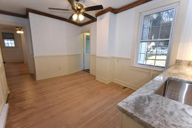 an empty room with wooden floor fan and windows