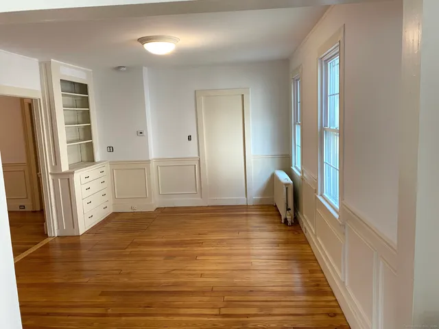 a view of a hallway with wooden floor and cabinet