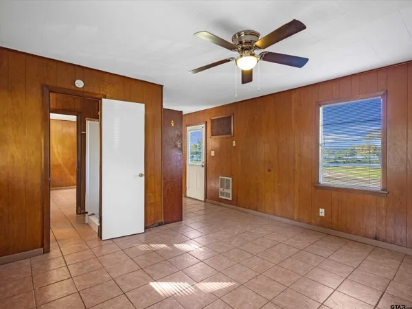 a view of an empty room with window and a ceiling fan