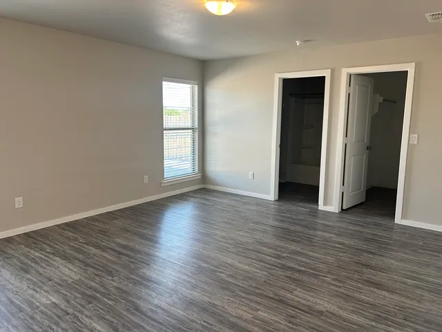 an empty room with wooden floor and windows