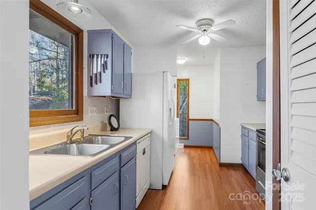 a kitchen with a sink a refrigerator and wooden floor