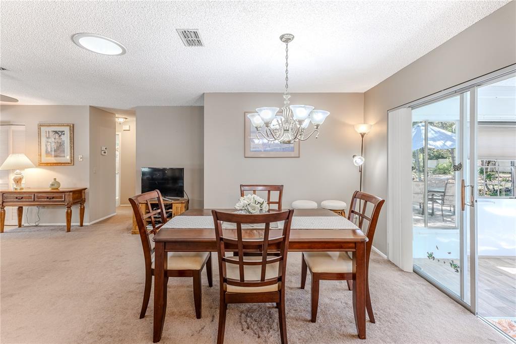 6375 Ocean Pines Lane Spring Hill, FL 34606 - Photo 12 of 50 a view of a dining room with furniture a chandelier and large windows