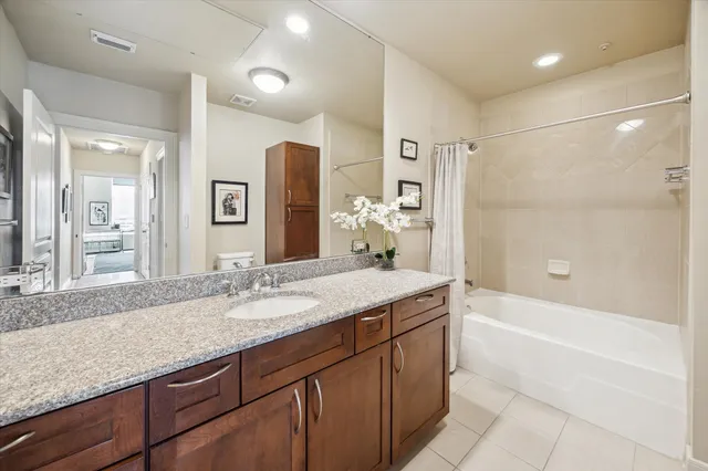 a bathroom with a granite countertop sink mirror and a bath tub