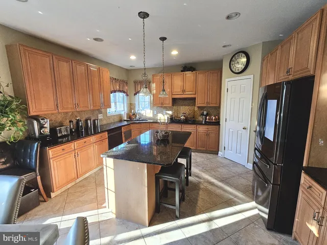 a kitchen with stainless steel appliances granite countertop a sink a stove a refrigerator cabinets and chairs