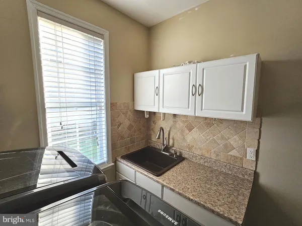 a kitchen with white cabinets appliances and a window