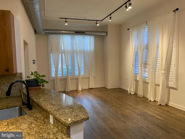 a kitchen with granite countertop a refrigerator a stove a sink and white cabinets with wooden floor