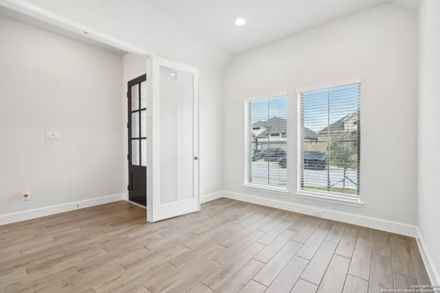 an empty room with wooden floor and windows