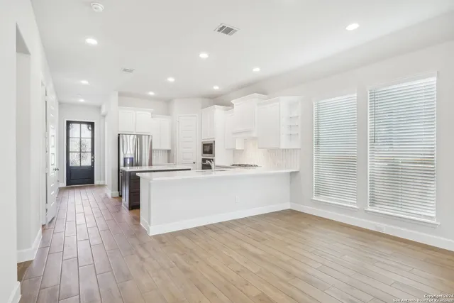 a large kitchen with a large counter top a sink stainless steel appliances and cabinets