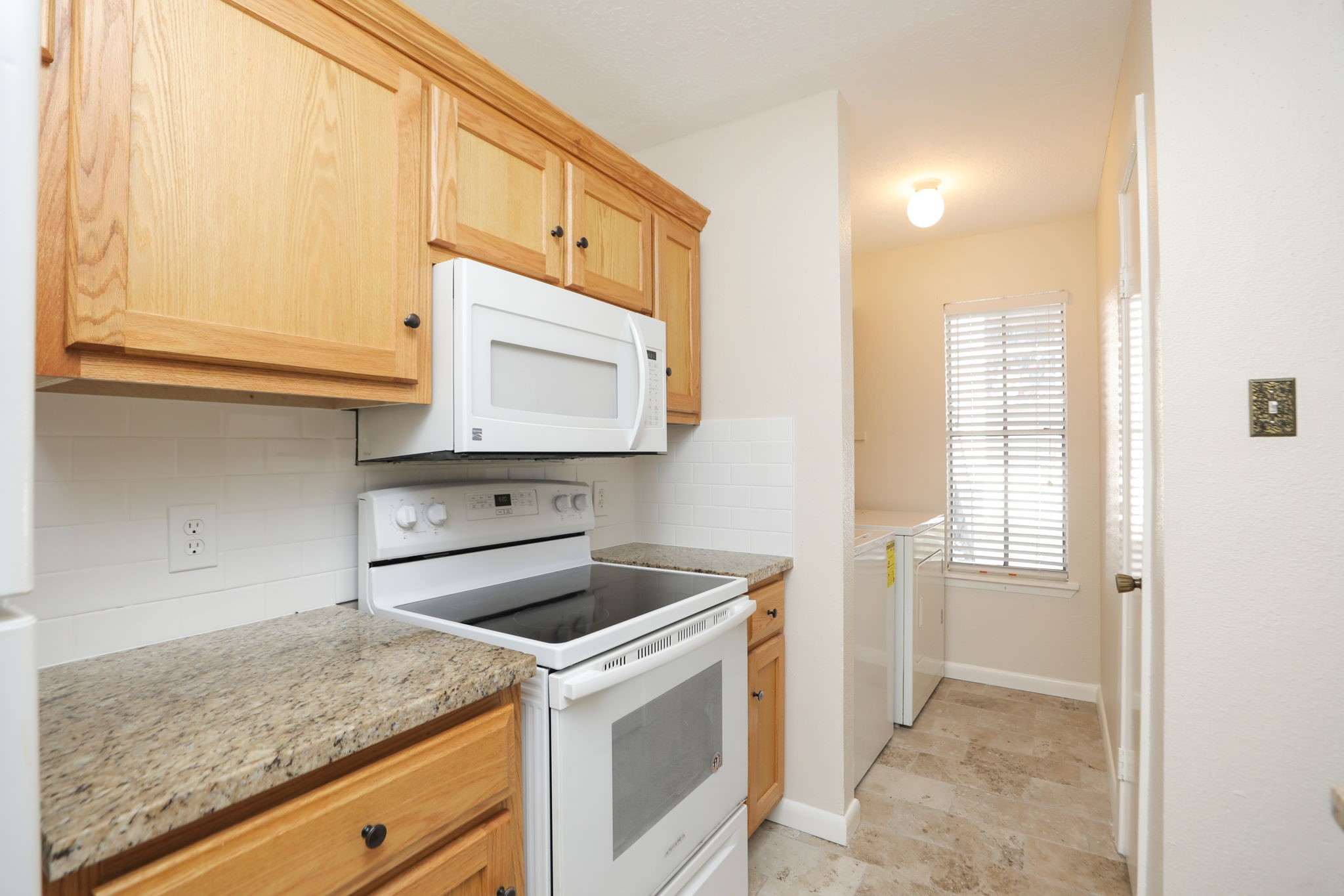 17401 Red Oak Drive, Unit 97 Houston, TX 77090 - Photo 17 of 37 a kitchen with granite countertop cabinets washer and dryer