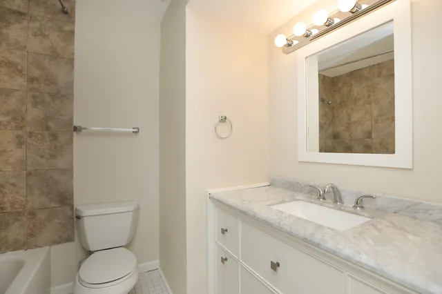 a bathroom with a granite countertop sink toilet and mirror
