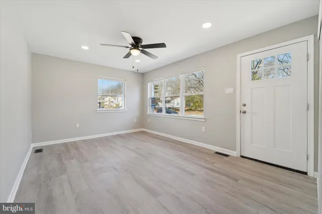 a view of an empty room with a window and wooden floor