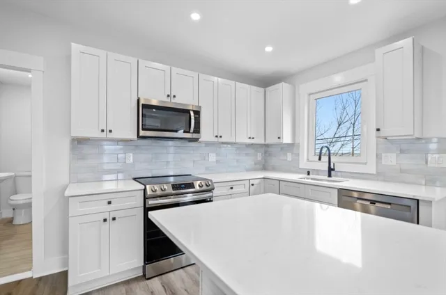 a kitchen with granite countertop a stove a sink and a microwave
