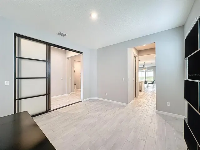 a kitchen with stainless steel appliances kitchen island granite countertop a stove a sink a refrigerator a stove a dining table and chairs with wooden floor