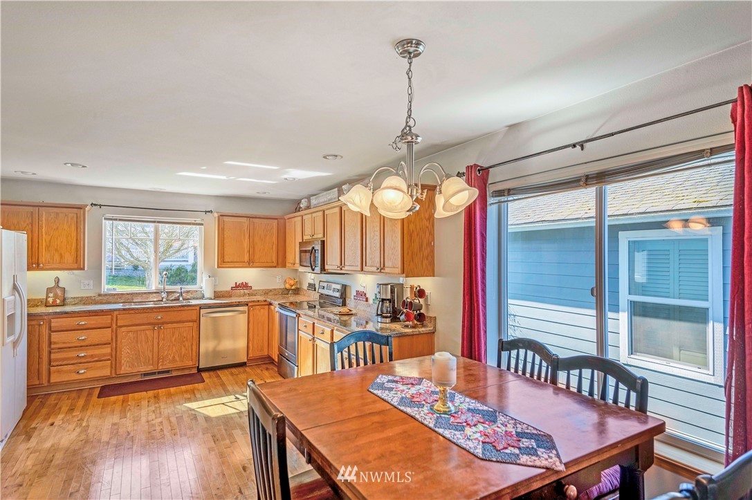 4139 Track Street Bellingham, WA 98226 - Photo 9 of 40 a kitchen with stainless steel appliances kitchen island granite countertop a table chairs in it and wooden floors
