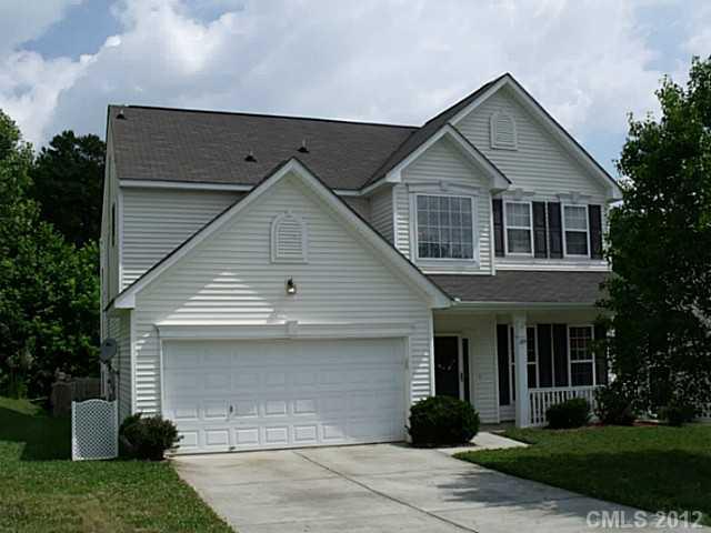 a front view of a house with a yard and trees