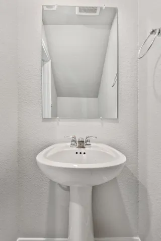 a white sink sitting under a bathroom mirror