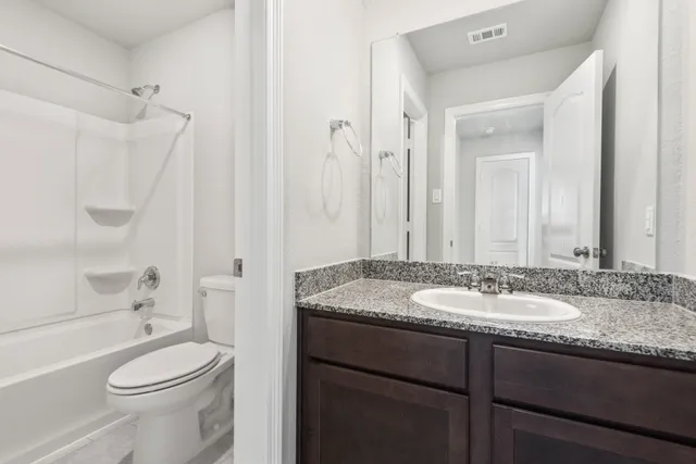 a bathroom with a granite countertop sink toilet a mirror and shower