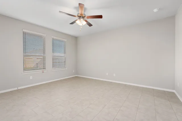 an empty room with windows and fan