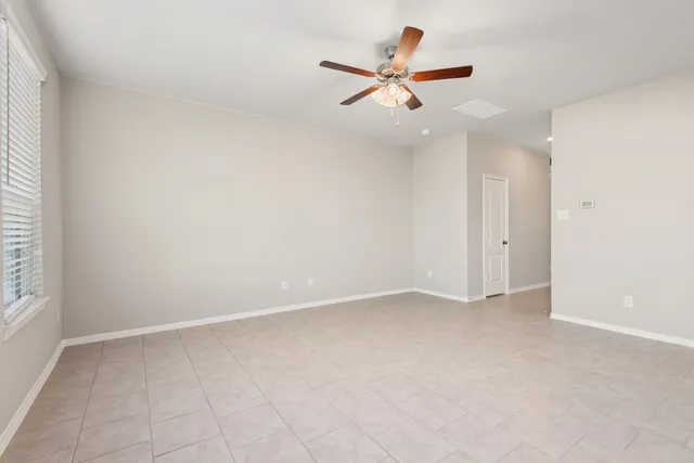 an empty room with ceiling fan and window