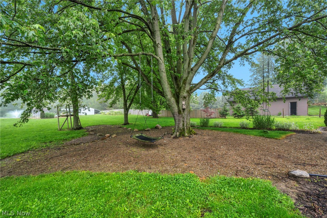 7996 Buffham Road Lodi, OH 44254 - Photo 40 of 50 Expansive exterior landscaping featuring mature trees, a mulched ground cover area, verdant lawn, and visible garden beds