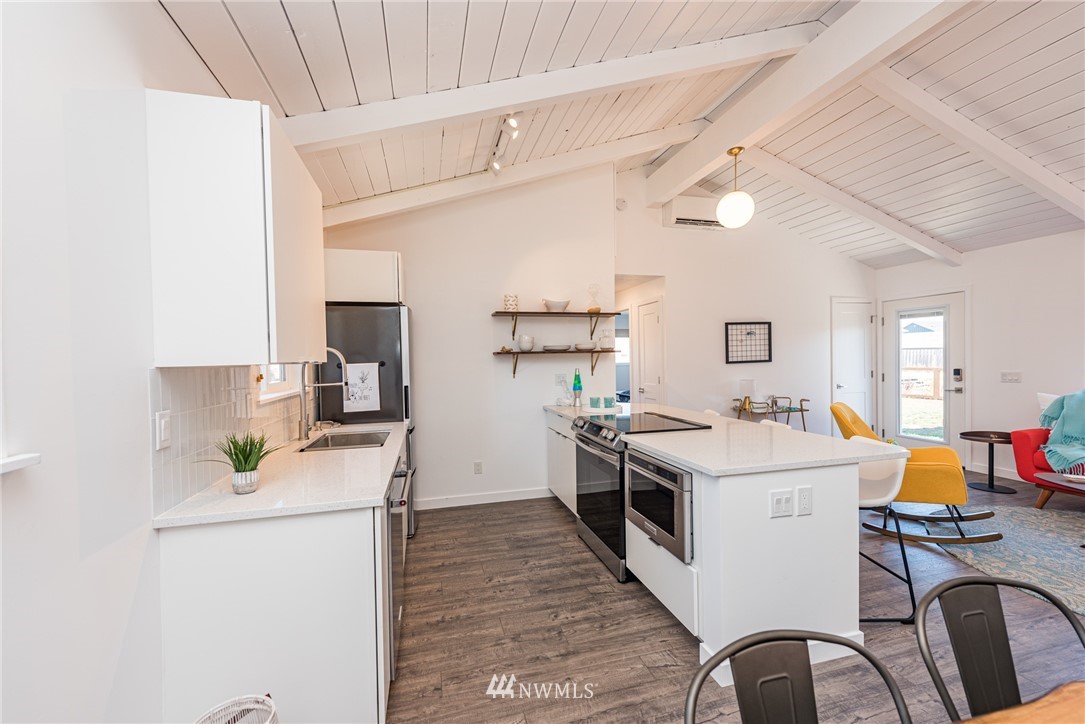 271 3 Crabs Road Sequim, WA 98382 - Photo 30 of 40 a kitchen with a sink a stove and chairs with wooden floor