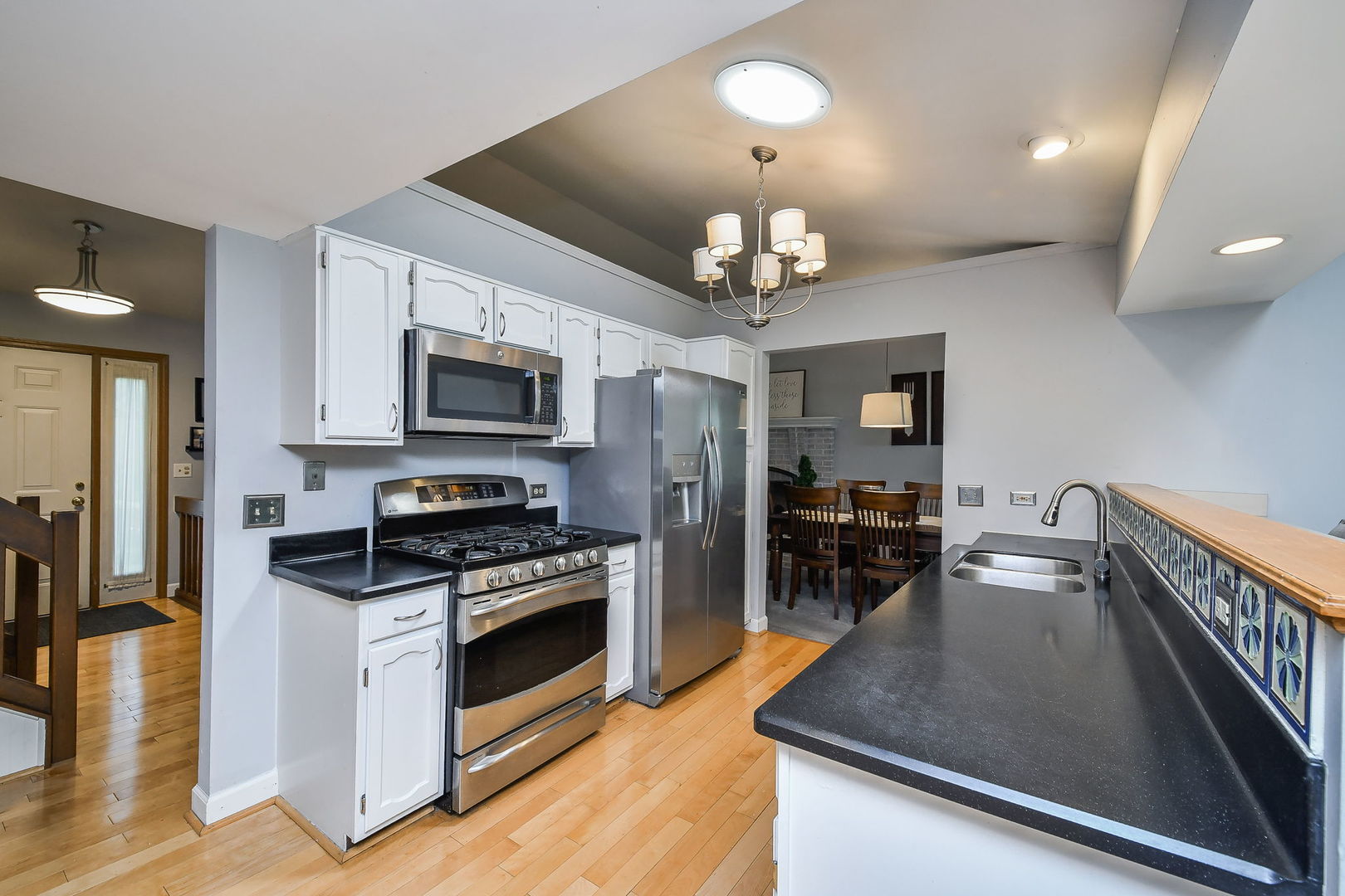27W108 Walnut Drive Winfield, IL 60190 - Photo 5 of 20 a kitchen with stainless steel appliances granite countertop a stove top oven a sink dishwasher a dining table and chairs with wooden floor