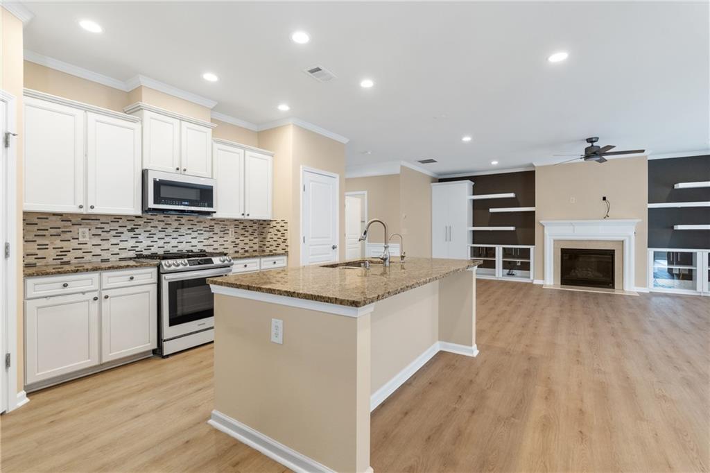 865 Great Glen Place Suwanee, GA 30024 - Photo 13 of 45 a kitchen with granite countertop a stove top oven and cabinets