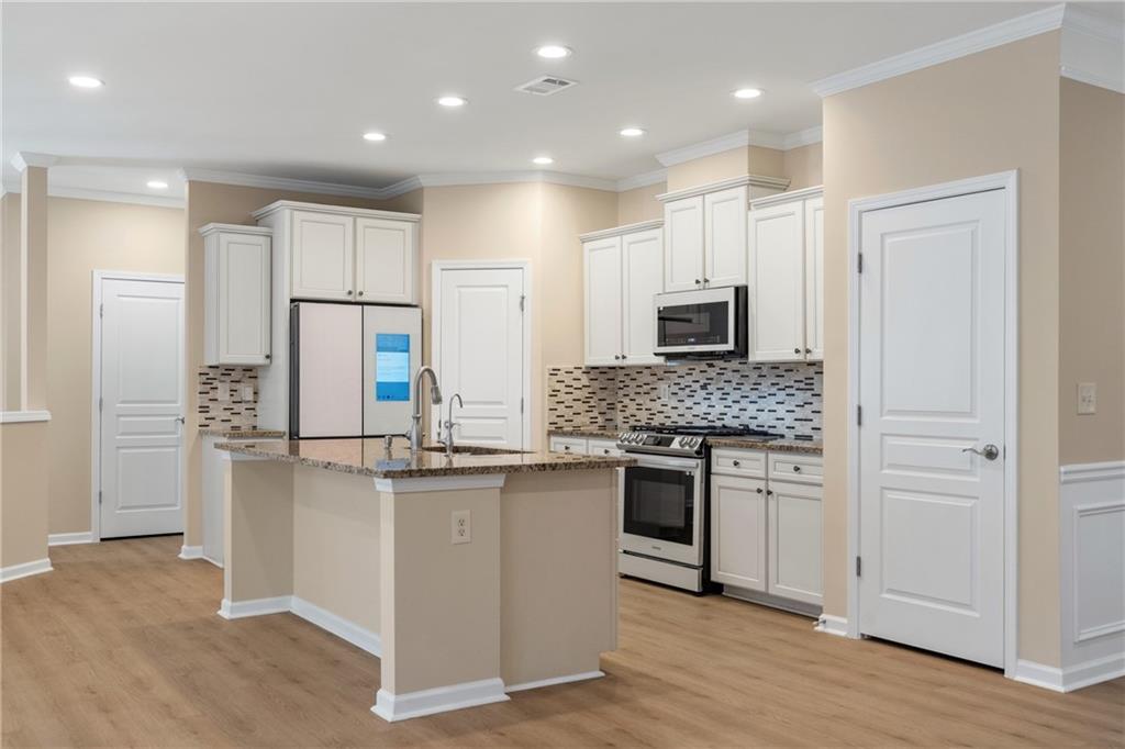 865 Great Glen Place Suwanee, GA 30024 - Photo 17 of 45 a kitchen with stainless steel appliances granite countertop a stove and a refrigerator