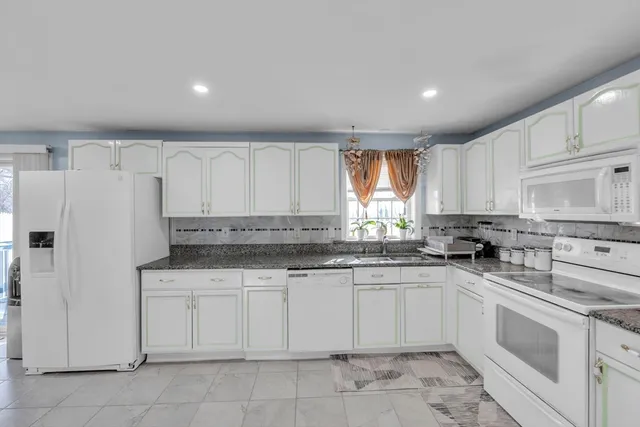 a kitchen with granite countertop white cabinets white appliances and sink