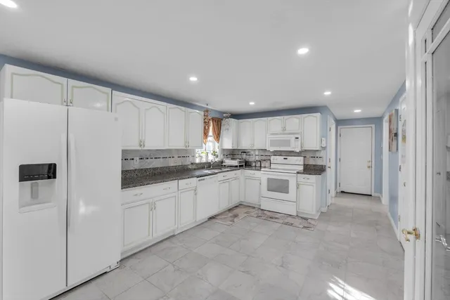a kitchen with granite countertop white refrigerator and white cabinets