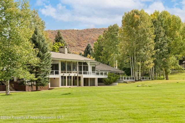 a view of a white house with a big yard and large trees