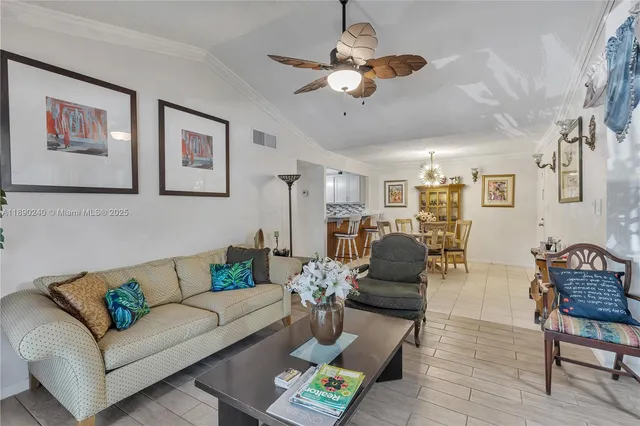 a living room with furniture potted plant and kitchen view