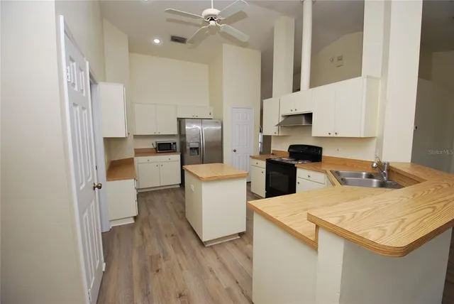 a kitchen with a sink a refrigerator and a stove top oven