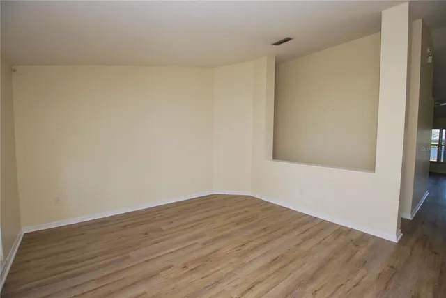 a view of an empty room with wooden floor and a window