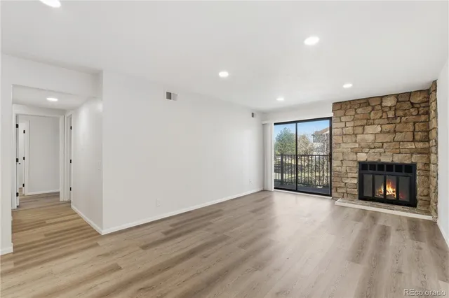 an empty room with wooden floor fireplace and windows