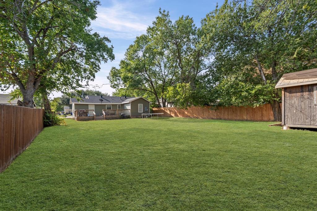 3605 Rolando Avenue Waco, TX 76711 - Photo 16 of 17 Spacious fenced backyard featuring a wood privacy fence, mature trees, a detached storage shed, and a rear deck